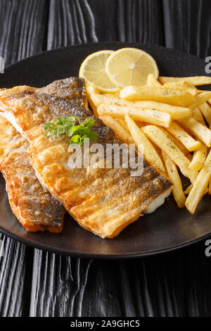 Lecker gegrilltes Barschfilet mit Pommes frites in der Nähe serviert auf einem Teller auf den Tisch. Vertikale Stockfoto