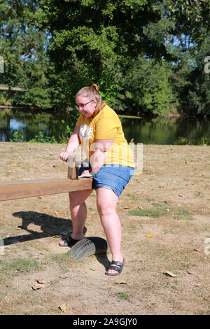 Übergewichtige junge Person auf einer Wippe. Stockfoto