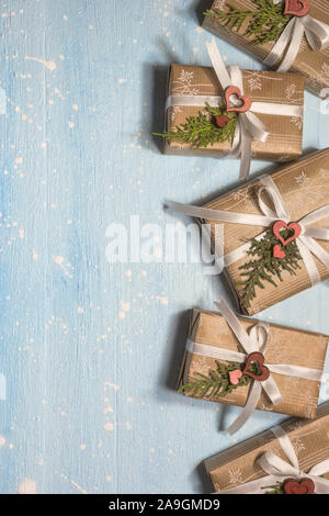 Weihnachten Geschenke verpackt in Handwerk Papier auf hellblauem Hintergrund. Urlaub und Feier Konzept für Postkarte oder eine Einladung. Ansicht von oben mit Co Stockfoto