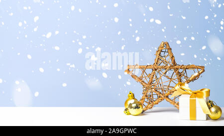 Kleine Weihnachten Geschenk Box mit goldenen Kugeln und Xmas star im Schnee auf blauem Hintergrund. Weihnachten, Neujahr, Winterurlaub Konzept Stockfoto