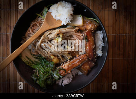 Asiatische Auberginen, Pilze, Kohl Pfannengerichte über Reis in schwarzem Stein Schüssel serviert. Stockfoto