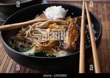 Asiatische Auberginen, Pilze, Kohl Pfannengerichte über Reis in schwarzem Stein Schüssel serviert. Stockfoto