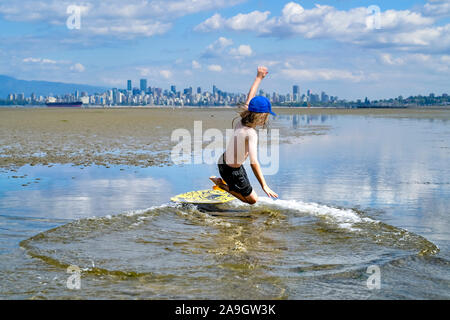 Die jungen langhaarigen Jungen skimboarding, Spanische Banken, English Bay, Vancouver, British Columbia, Kanada Stockfoto