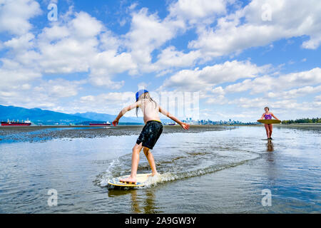 Die jungen langhaarigen Jungen skimboarding, Spanische Banken, English Bay, Vancouver, British Columbia, Kanada Stockfoto