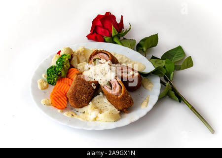 Karadjordjeva Steak, es ist eine gewalzte Kalb- oder Schweinefleisch Schnitzel, mit Kartoffelpüree pettitoes, gekochtem Gemüse, Alfredo Sauce und eine rote Rose als Dekoration Stockfoto