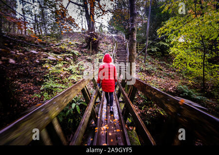 Ein junger Frauen zum Wandern, quer und alte Holzbrücke in Großbritannien Landschaft an einem kalten Wintertag, Wandern ein Hausberg Route, Stockfoto