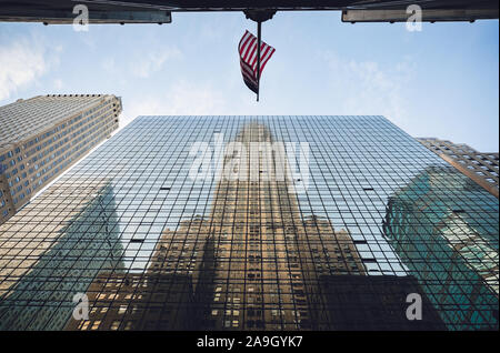 Reflexion des Chrysler Building auf der gegenüberliegenden Wolkenkratzer und die amerikanische Flagge, New York City Stockfoto