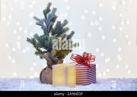 Winterurlaub noch Leben von Square elektrische Kerze, kleiner Baum und verpackte Geschenk sitzen auf Schnee. Stockfoto