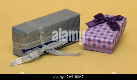 Schöne bunte Geschenkboxen mit Bögen und Silber Glitter Band auf gelbem Hintergrund Stockfoto