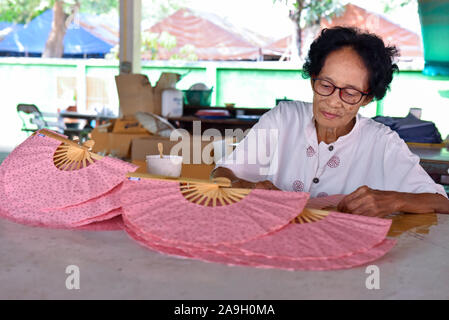 Alte Lady, die Hand Fans in Bo Sang weiter nach Chiang Mai, Thailand Stockfoto