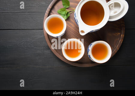 Tassen grünen Tee mit Minze und Wasserkocher auf dunklem Hintergrund. Chinesische Konzept. Blick von oben. Asiatische noch leben. Stockfoto