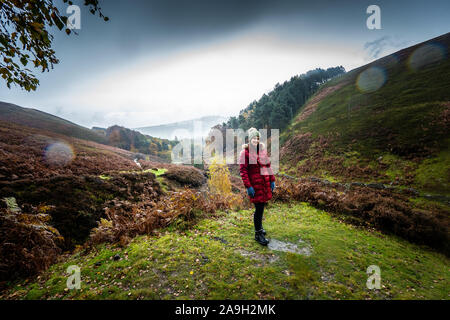 Eine junge Frau, Wanderer, Kletterer nimmt einen Bruch von einen Berg klettern und posiert für ein Foto beim Stehen im kalten Winter regen Stockfoto