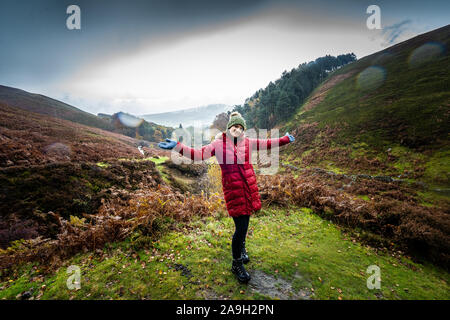 Eine junge Frau, Wanderer, Kletterer nimmt einen Bruch von einen Berg klettern und posiert für ein Foto beim Stehen im kalten Winter regen Stockfoto