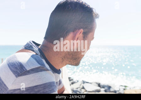 Von hinten ein Mann sitzt auf der Promenade bis zum Horizont auf der Suche Stockfoto