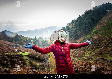 Eine junge Frau, Wanderer, Kletterer nimmt einen Bruch von einen Berg klettern und posiert für ein Foto beim Stehen im kalten Winter regen Stockfoto