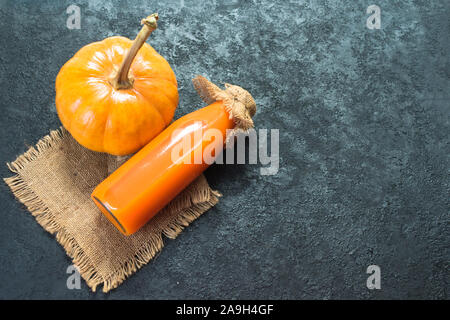 Kürbis Saft in eine Flasche und einen Kürbis auf schwarzem Hintergrund. Die Aussicht von oben. Kopieren Sie Platz. Stockfoto