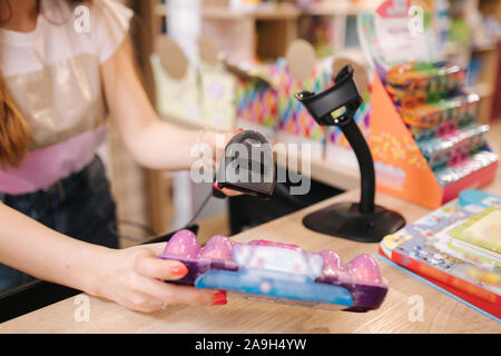 Junge kaukasier weiblich Frau Kassierer in Toy Store. Frau verwenden Kassierer Zähler in kids Mall. Stockfoto