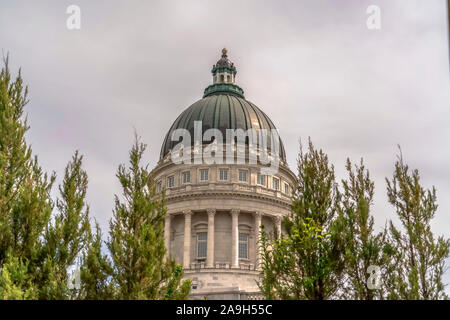 Berühmte Utah State Capitol Building Dome umrahmt von Bäumen gegen bewölkter Himmel Stockfoto