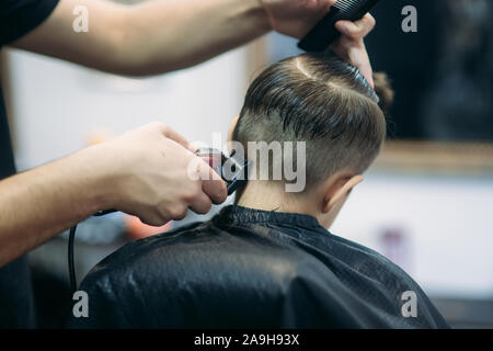 Kleiner Junge auf einem Haarschnitt im Friseur sitzt auf einem Stuhl. Stockfoto