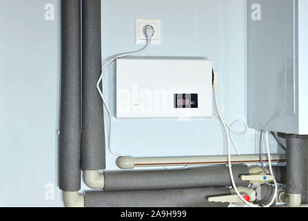 Kompakte Wand Automatischer Spannungsregler (AVR) für Gas Boiler zu schützen. Manometer im Kesselraum in der Nähe der Heizrohre mit Isolierung Beschichtung. Stockfoto