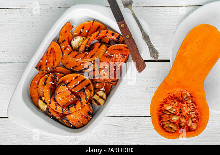 Gegrillte butternut Kürbis Schichten auf weißem Holz- Hintergrund. Gesunde organische Diät essen für die Mittagspause. Ansicht von oben Stockfoto