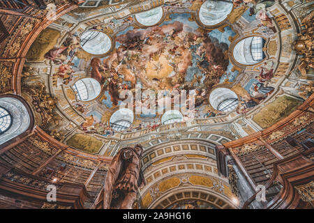 Wien, Österreich - 28. April 2019: Blick nach oben von Deckenfresko im kaiserlichen Bibliothek mit Kaiser Karl VI. Statue Stockfoto