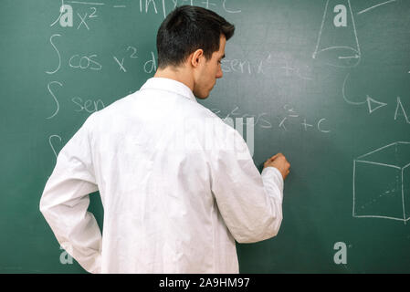 Studenten im Labor Klasse, mit weißen Mantel, Schreiben auf der Schiefertafel. Stockfoto