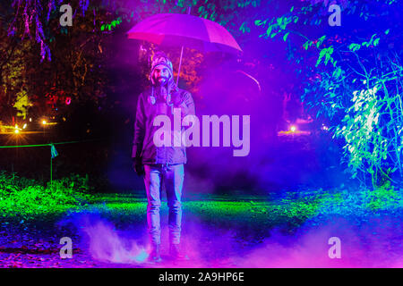 Syon Park, London, Großbritannien, 15. November 2019. Ein Mann geht durch eine mystische Nebel und beleuchtete verlässt. Illuminationen Der verzauberte Wald" im Syon Park und rund um den historischen Syon House wieder öffnet für die Öffentlichkeit mit einer Spur der schön beleuchteten Szenen rund um den Park und das historische Syon House mit seiner großen Wintergarten und Lasershow im Inneren. Verzauberte Wälder wird geöffnet, freitags, sonntags 15. Nov, 1. Dez, 2019. Credit: Imageplotter/Alamy leben Nachrichten Stockfoto