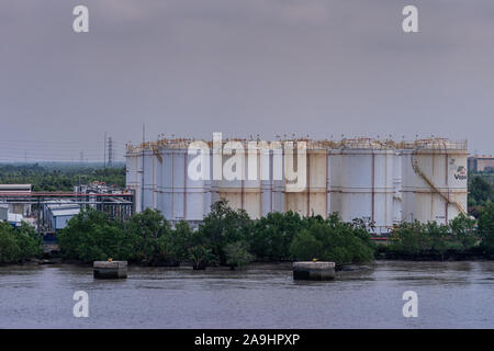 Lange Tau Fluss, Vietnam - 12. März 2019: Phuoc Khanh. Nahaufnahme des Cluster von PetroVietnam weißen Panzern konfrontierten durch grünes Laub unter braun-blau s Stockfoto