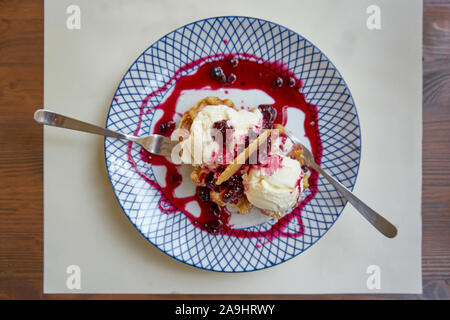 Vanilleeis serviert auf einem Teller mit Waldbeeren Dressing und Wafer Stockfoto