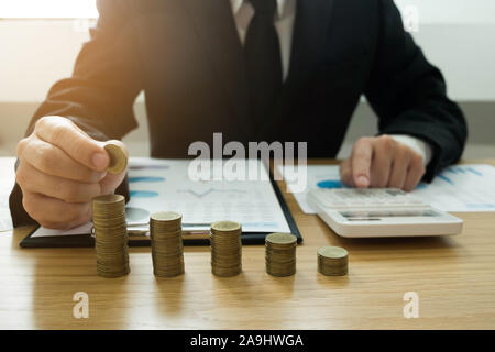 Geschäftsmann nimmt Münzen auf den Tisch und zählt Geld. Geschäftskonzept. Stockfoto