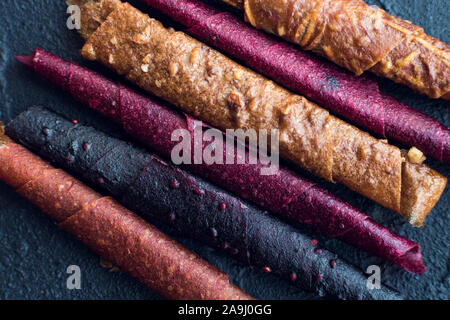 Süße püriertes Obst Roll-up pastila. Hausgemachte Obst Leder von Apfel, Aprikose, Erdbeere und Heidelbeere auf schwarzem Hintergrund. Obst rollen. Getrocknete Früchte. Stockfoto