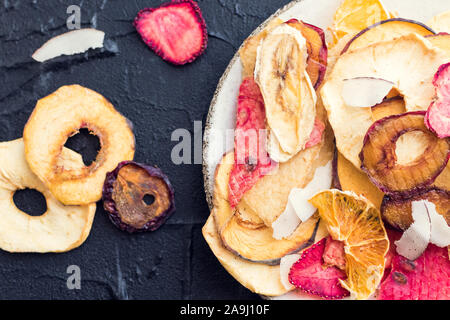 Gesunde hausgemachte Frucht Chips von Apple, Orange, Banane, Erdbeere auf grauem Hintergrund. Bio Diät essen. Die vegane Ernährung. Getrocknete Früchte. Vegetarische pl Stockfoto