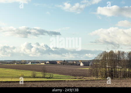 Blick auf das Dorf aus dem gepflügten Feldern. Wohnhäuser, Scheunen, Ausrüstung. Bäume im Vordergrund. Podlachien. Polen. Stockfoto