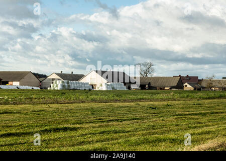 In den späten Herbst. Blick auf das Dorf von der grünen Wiese. Wohnhäuser, Scheunen, Silageballen. Industrial Dairy Farm. Podlachien. Polen. Stockfoto