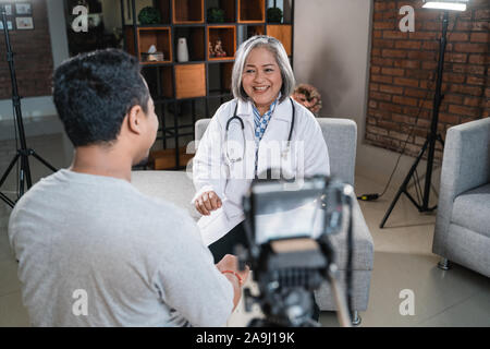 Arzt im Gespräch mit dem Patienten und die Aufnahme mit Kamera Stockfoto
