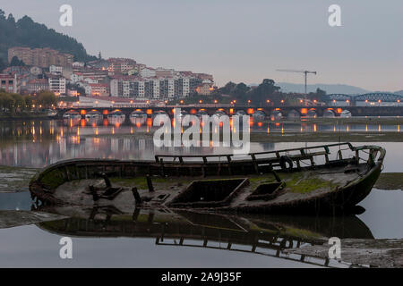 Alten hölzernen Boot Verfallende im Sand Eume Fluss Pontedeume im Hintergrund mit beleuchtete Brücke La Coruña Galicien Spanien Stockfoto