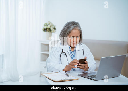 Ältere Frau Doktor mit Smartphone Stockfoto