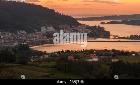 Serene Dämmerung Blick auf das mittelalterliche Fischerdorf Pontedeume mit seinen Eisen und Stein Brücke orange sky La Coruña Galicien Spanien Stockfoto