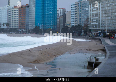 Große Wellen auf der Promenade von La Coruña mit der Stadt Gebäude im Hintergrund brechen Stockfoto