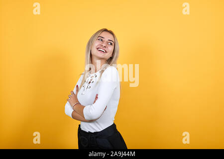 Lächelnde Frau in legere Kleidung, Hände gekreuzt, auf orange Wand isoliert Stockfoto