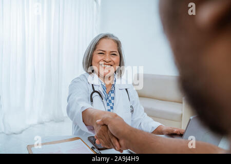 Arzt und Patient, die Hände schütteln Stockfoto