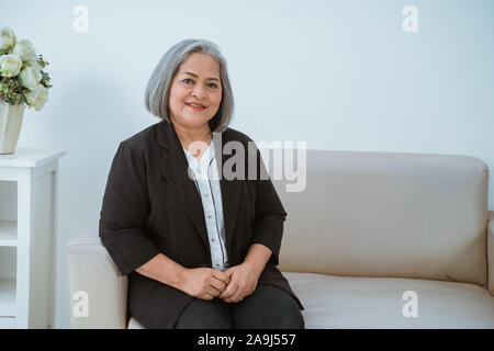 Alte Frau ist zuversichtlich, Ernst schön sitzen auf der Couch Stockfoto