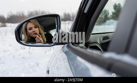 Blonde Frau, die in der Auto Rückspiegel und die Farbe der Lippen. Stockfoto