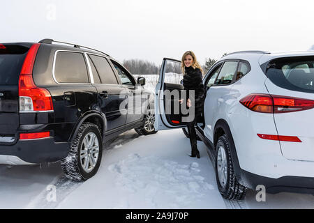 Die blonde Frau aus dem weißen suv Auto und blickt zurück. Stockfoto