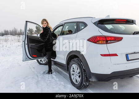 Die blonde Frau aus dem weißen suv Auto und blickt zurück. Stockfoto