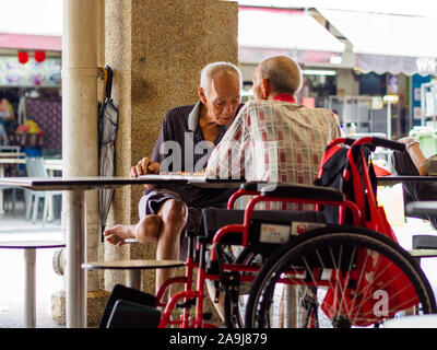 Singapur, 12. Apr 2019 - Zwei alte Männliche Pensionäre/Rentner ein Spiel des chinesischen Schach in einer Hawker Center genießen. Singapur hat eine rasch alternde Bevölkerung Stockfoto