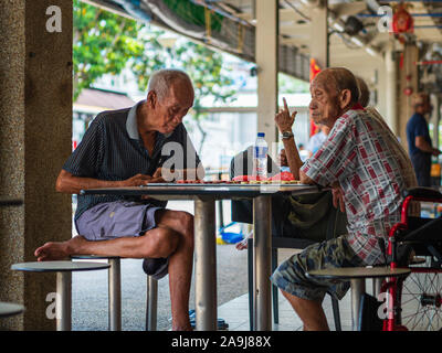 Singapur, 12. Apr 2019 - Alte Männliche Pensionäre/Rentner genießen Sie eine Partie Schach in einer Hawker Center. Singapur hat eine rasch alternde Bevölkerung Stockfoto