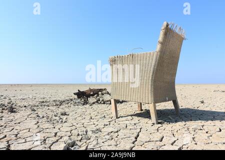 Einsame Stuhl in der unwirtlichen Landschaft mit gesprungenen Boden unter einem blauen Himmel. Bild mit kopieren. Stockfoto