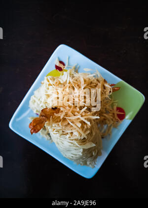 Gebratene Garnelen, die mit Nudeln bestrichen wurden, die als Udang Sanggul auf einem bunten Teller auf einem Holztisch bekannt sind. Stockfoto